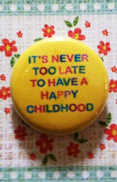 a yellow button that says it's never too late to have a happy childhood