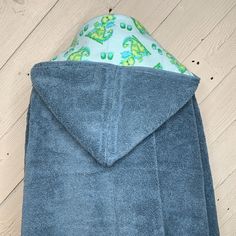 a blue towel is folded on top of a wooden floor with a green frog print