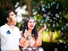 a man and woman sitting on a bench with bubbles in the air above their heads