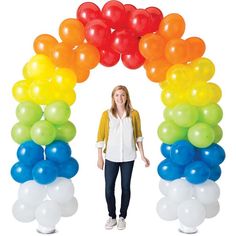 a woman standing in front of an arch made out of balloons