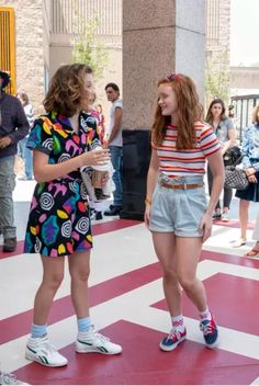 two young women standing next to each other on a red and white checkered floor