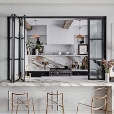 an open kitchen with marble counter tops and bar stools in front of the window