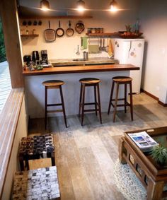 an open kitchen with three stools in it