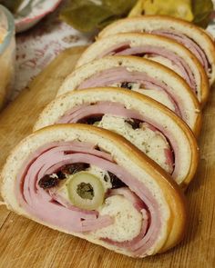 ham and olive sandwich cut in half on a cutting board with other food items nearby