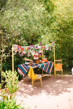 an outdoor table with colorful blankets and chairs