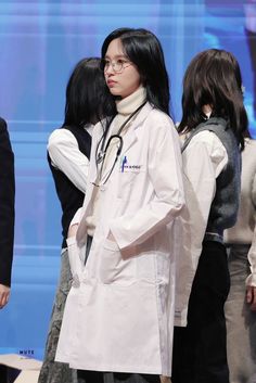 a group of people standing around each other in front of a blue screen and wearing white lab coats