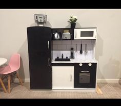 a small kitchen with black and white appliances in the corner next to a pink chair