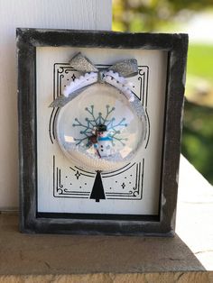 a white and black frame holding a snowman ornament in it's center