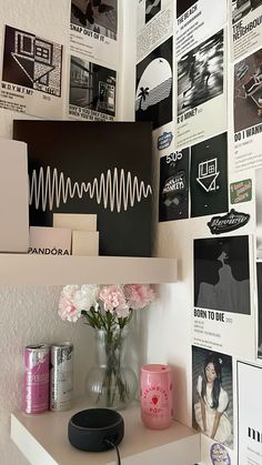 a white shelf topped with lots of pictures and vases filled with pink flowers on top of it