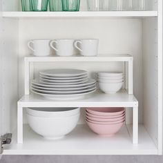 dishes and cups are stacked on the shelves