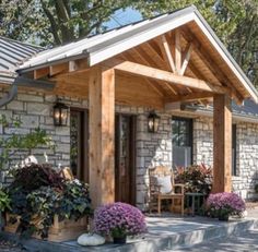 a small house with lots of plants and flowers on the front porch, covered in wood