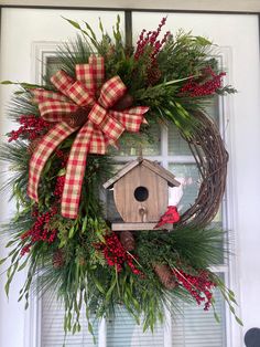 a wreath with a birdhouse hanging on the front door