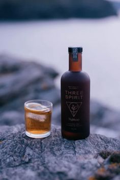 a bottle and glass sitting on top of a rock