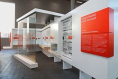 an exhibit with white walls and red accents