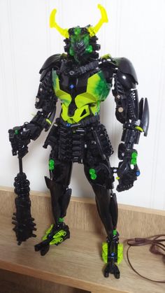 a black and green robot standing on top of a wooden table