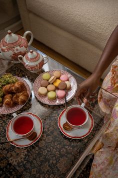 a table topped with plates of food and cups of tea next to each other on top of a carpeted floor