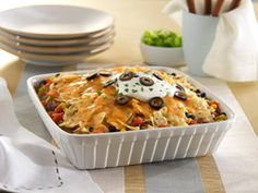 a casserole dish is sitting on a table with plates and utensils