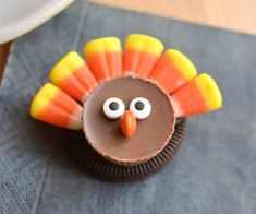 a cupcake decorated like a turkey on top of a blue napkin with candy eyes