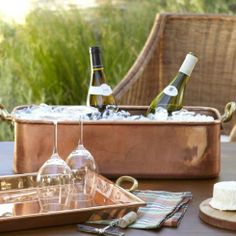 two wine glasses and some bottles on a table