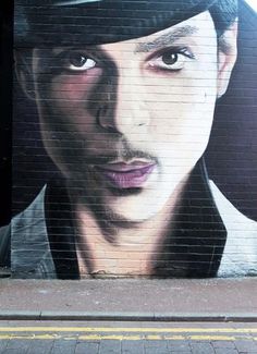 a large painting of a man wearing a hat on the side of a building