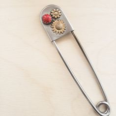 This keychain is the perfect gift for the new driver in your family.   The extra large safety pin is 5 inches long and features two soldered brass sunflowers and a red synthetic turquoise stone. Safety Pin Keychain, Giant Safety Pin, Pin Keychain, Large Safety Pin, New Driver, New Drivers, Trench Coats Women, Safety Pin, Turquoise Stone