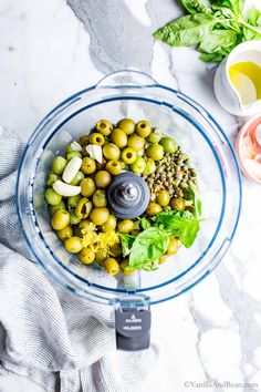 a food processor filled with olives and lettuce on top of a table