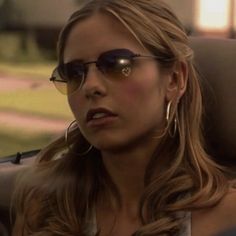 a woman wearing sunglasses sitting in the back seat of a car looking off to the side