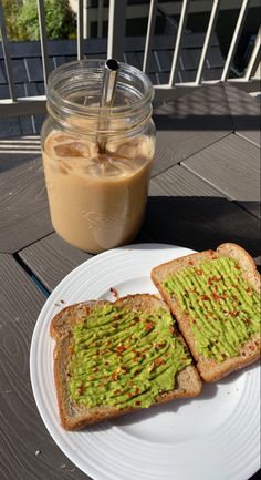 two pieces of bread on a white plate next to a jar of coffee and a drink