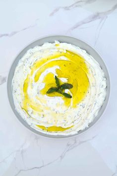 a bowl filled with hummus and sauce on top of a white table