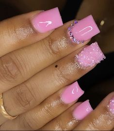 a woman's hand with pink and white nail polish on her nails, holding a gold ring