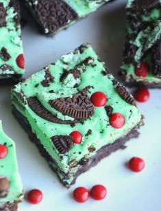 there are many pieces of cake with green frosting and red berries on the plate