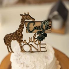 a giraffe cake topper sitting on top of a white frosted cake