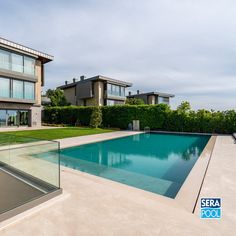 an empty swimming pool in front of two large houses with glass balconies on each side