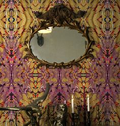 a mirror sitting on top of a wooden table next to a vase and candle holders