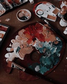 an artist's palette with paint, brushes and other art supplies on the table