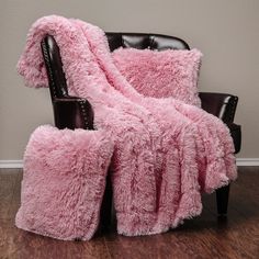 a chair with a pink blanket on top of it next to a black leather chair