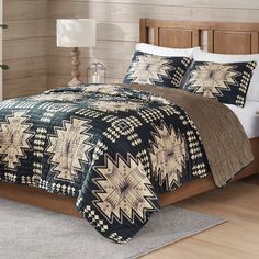 a bed with a black and tan comforter on top of it in a bedroom