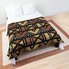 a bed covered in a brown and black comforter on top of a wooden floor