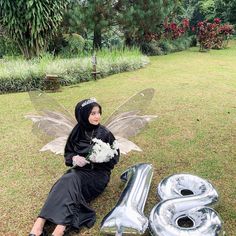 a woman sitting on the ground next to an air filled number 8 balloon in front of her