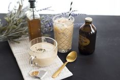 a table topped with two cups filled with liquid next to bottles of alcohol and spoons