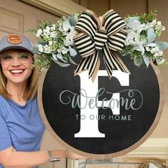 a woman standing in front of a welcome sign with a bow on it's head