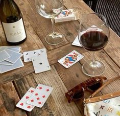 wine, playing cards and sunglasses on a wooden table