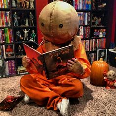 a stuffed animal reading a book in front of a bookshelf filled with toys