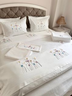 a white bed topped with lots of pillows next to a night stand and nightstands