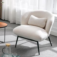 a white chair sitting on top of a carpeted floor next to a vase with flowers