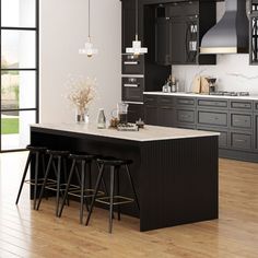 a large kitchen with black cabinets and white counter tops, along with bar stools