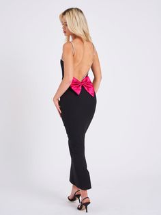 the back of a woman wearing a black and pink dress with a large bow on it