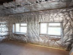 an unfinished room with aluminum foil on the walls and windows in place for insulation work