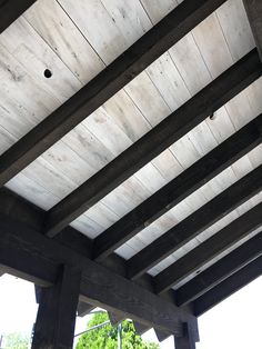 the underside of a wooden structure with wood slats on it and trees in the background