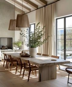 a dining room table and chairs in front of large windows